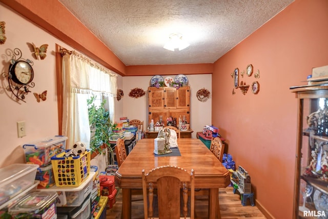 dining space with baseboards, a textured ceiling, and wood finished floors