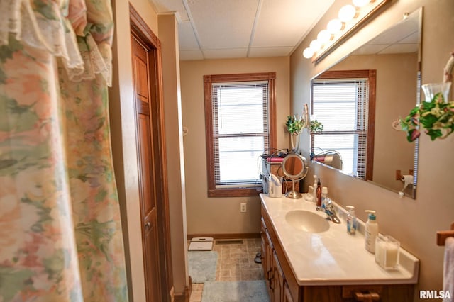 bathroom with visible vents, baseboards, a drop ceiling, and vanity