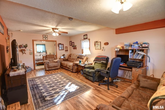 living area featuring a ceiling fan, arched walkways, a textured ceiling, and wood finished floors