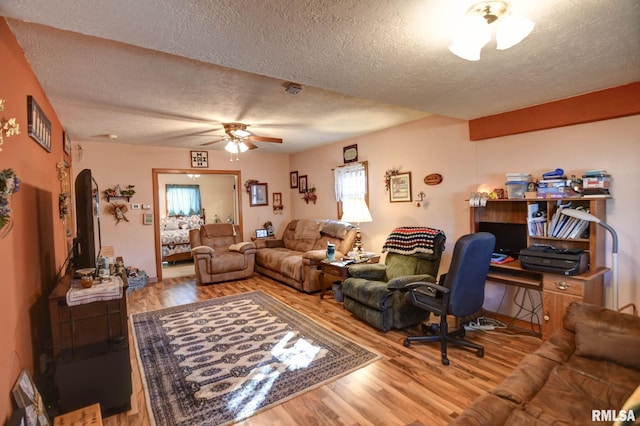 living room with ceiling fan, a textured ceiling, and wood finished floors