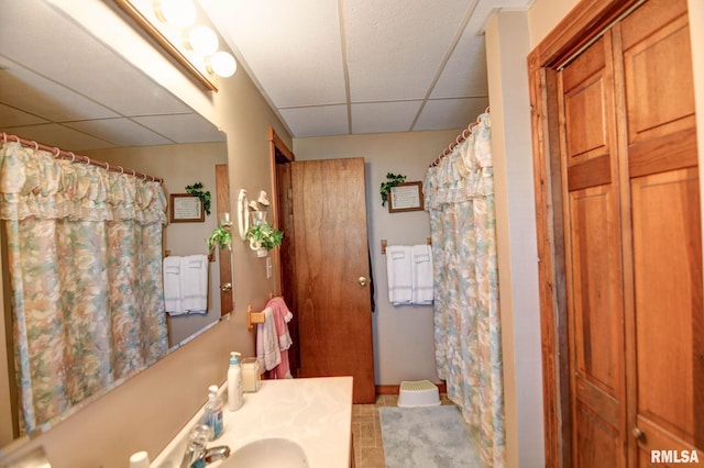 bathroom with a shower with shower curtain, a drop ceiling, and vanity