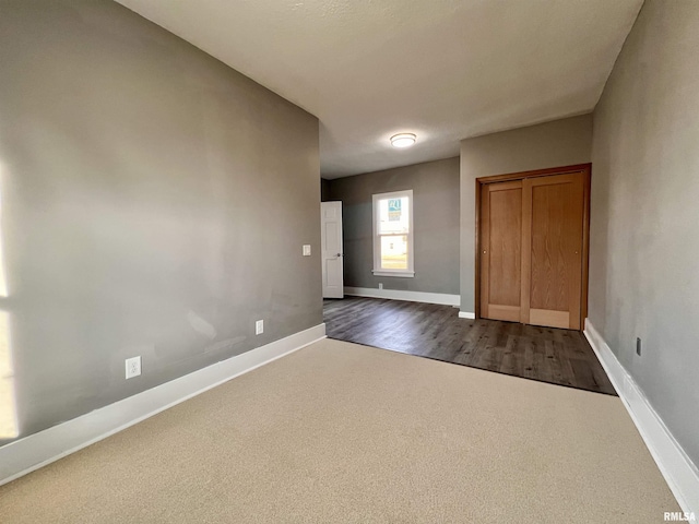 empty room with dark colored carpet and baseboards