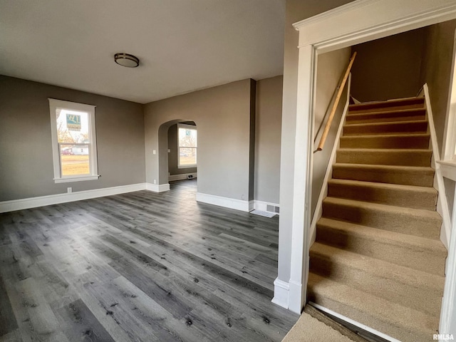 interior space with arched walkways, wood finished floors, and baseboards