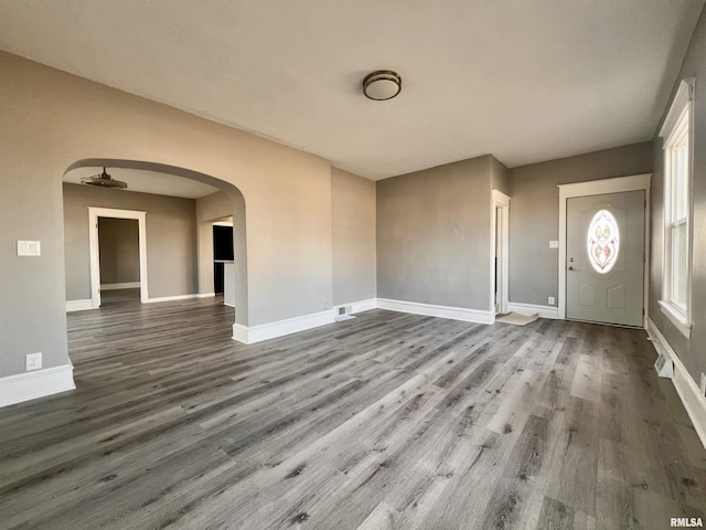 entryway with arched walkways, wood finished floors, visible vents, and baseboards