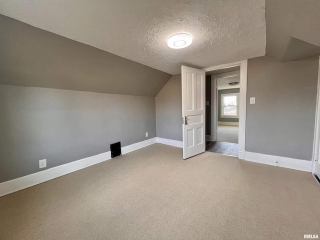 bonus room with a textured ceiling, carpet floors, lofted ceiling, and baseboards