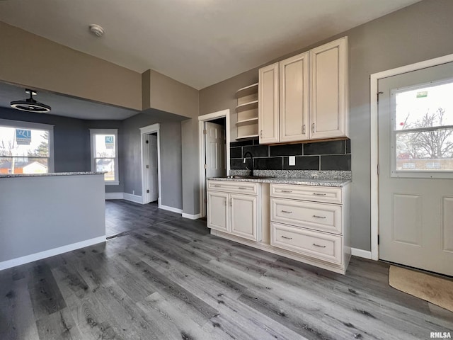 kitchen featuring backsplash, dark wood-style flooring, open shelves, and a sink