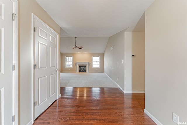 unfurnished living room featuring a fireplace, wood finished floors, a ceiling fan, and baseboards