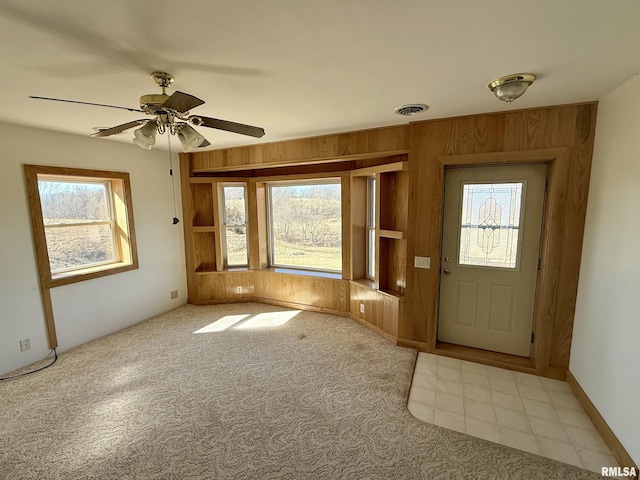 doorway to outside featuring carpet floors, a wealth of natural light, visible vents, and wooden walls