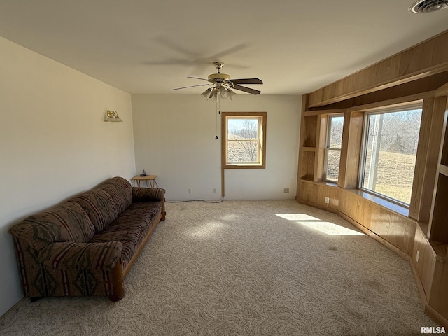 living area with a ceiling fan, carpet, visible vents, and a wealth of natural light