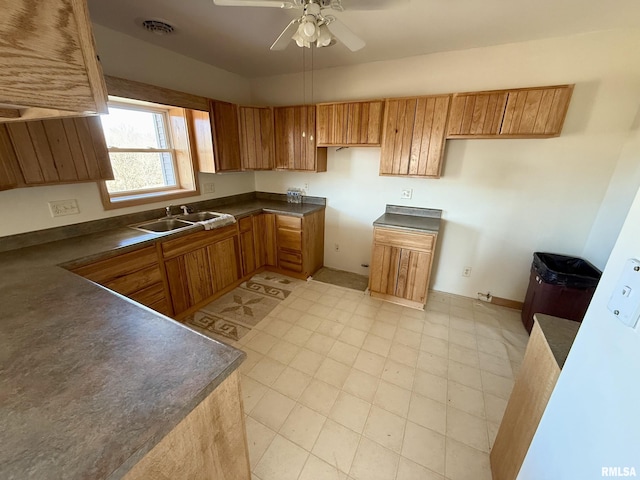 kitchen with dark countertops, a sink, visible vents, and brown cabinets