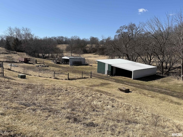 view of yard featuring an outbuilding, a rural view, an outdoor structure, and fence