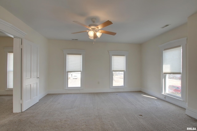 empty room featuring carpet floors, visible vents, and ceiling fan