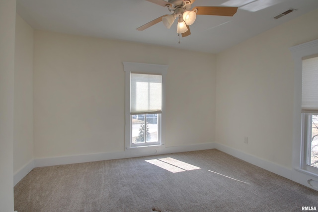 carpeted spare room with baseboards, visible vents, and ceiling fan