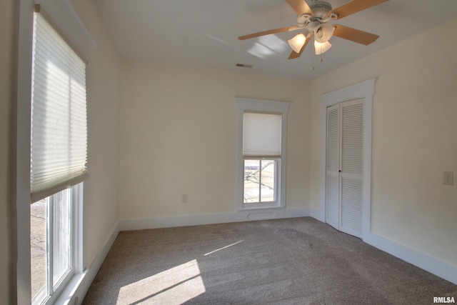 empty room featuring a ceiling fan, carpet, visible vents, and baseboards