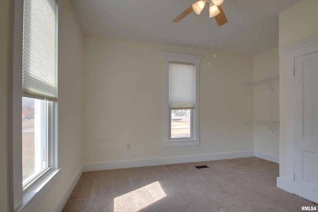 carpeted empty room featuring a ceiling fan, visible vents, and baseboards