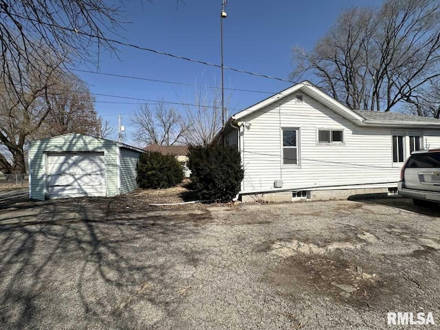 view of side of home with an outbuilding, aphalt driveway, and a detached garage