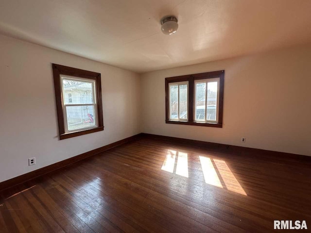 empty room with dark wood-style flooring and baseboards