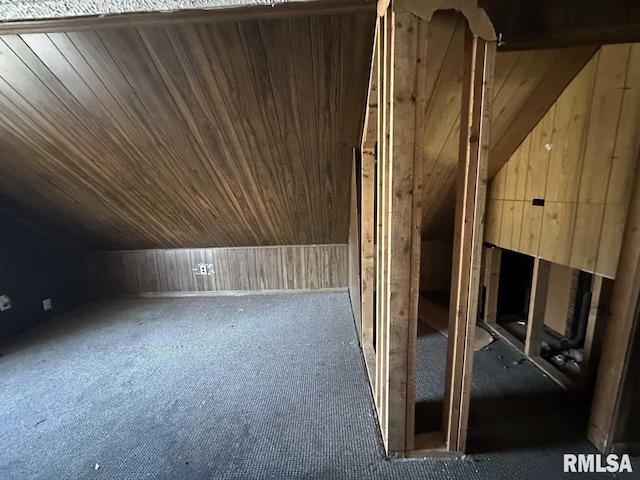 additional living space featuring vaulted ceiling and wooden walls