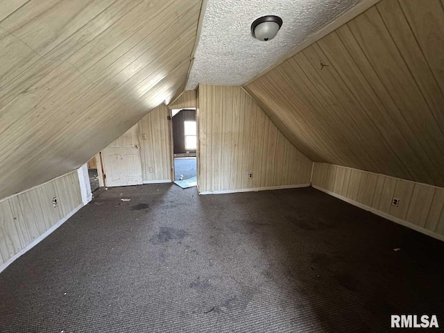 additional living space with carpet floors, vaulted ceiling, wooden walls, and baseboards