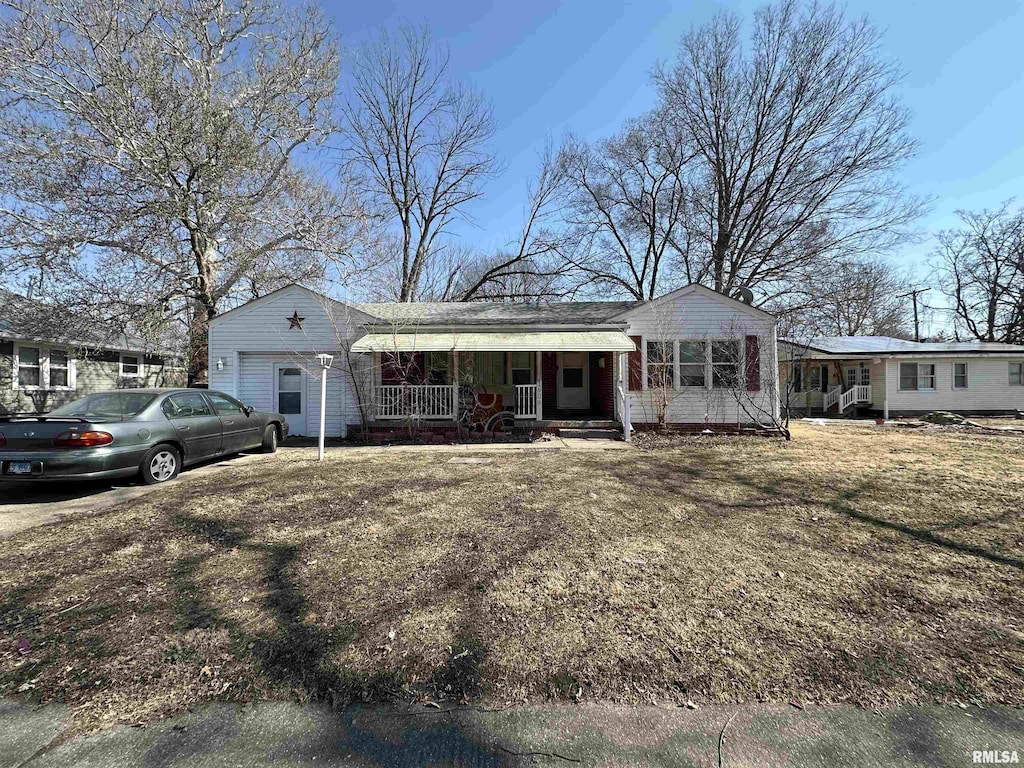 ranch-style house featuring covered porch, a front yard, and an attached garage