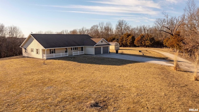 view of front of home with covered porch, driveway, a front lawn, and an attached garage