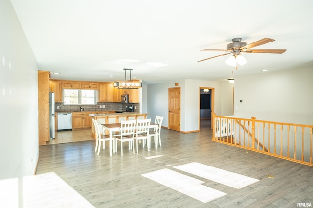 kitchen with stainless steel appliances, tasteful backsplash, light countertops, and light wood-style flooring