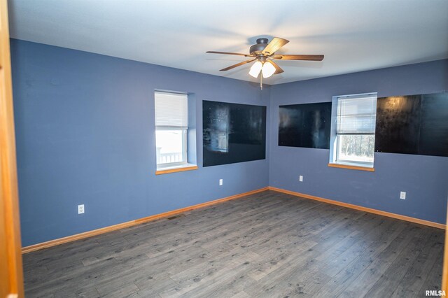 unfurnished room featuring a wealth of natural light, a ceiling fan, baseboards, and wood finished floors