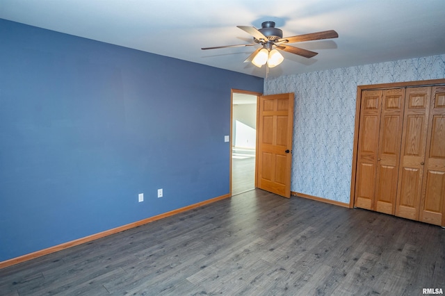 unfurnished bedroom with a closet, wallpapered walls, baseboards, and wood finished floors