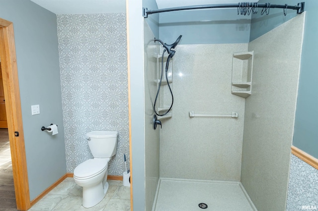bathroom featuring a stall shower, baseboards, and toilet