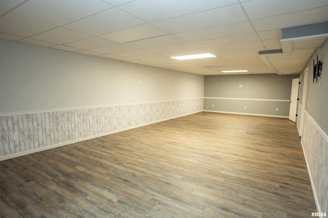 finished basement featuring baseboards, wainscoting, a drop ceiling, and wood finished floors