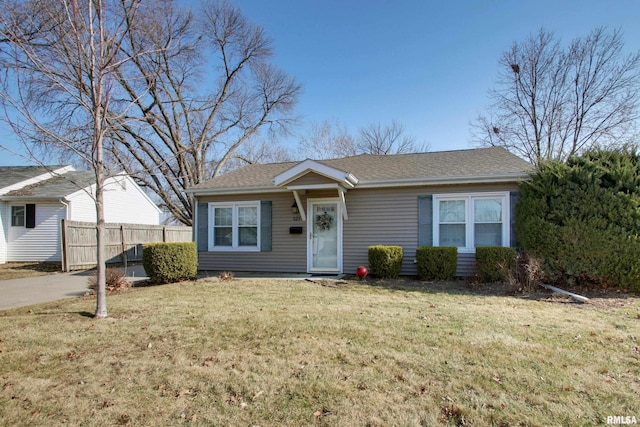 single story home with a front yard, roof with shingles, and fence