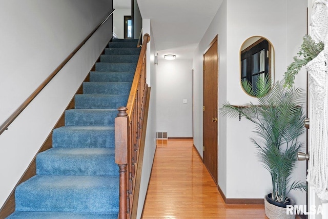 stairway featuring visible vents and wood finished floors