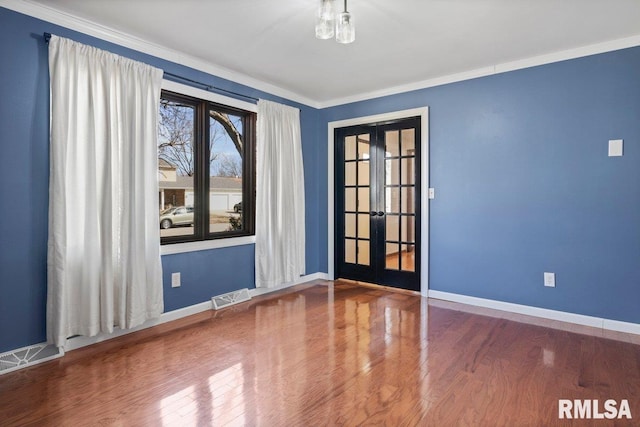 unfurnished room with wood finished floors, visible vents, baseboards, french doors, and crown molding