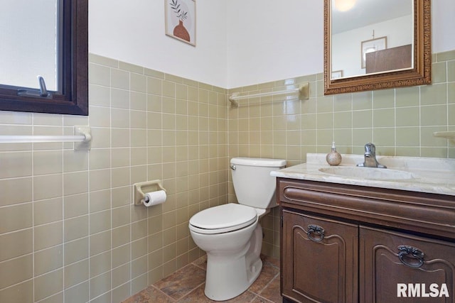 bathroom featuring tile patterned floors, vanity, toilet, and tile walls