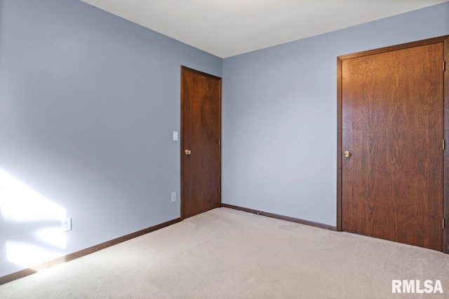 spare room featuring light carpet and baseboards