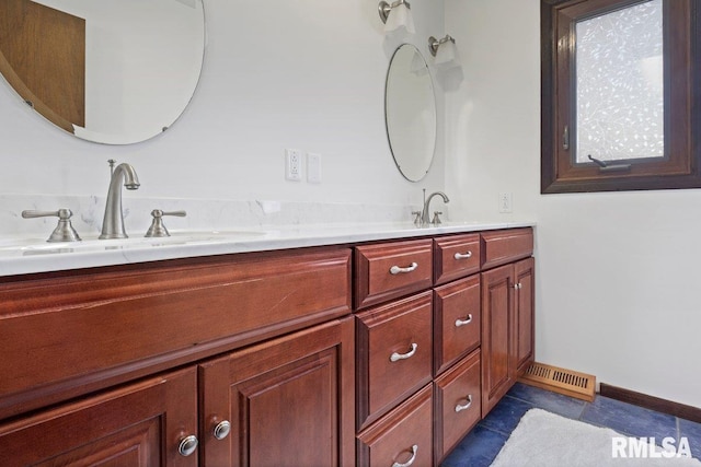 bathroom featuring visible vents, a sink, baseboards, and double vanity