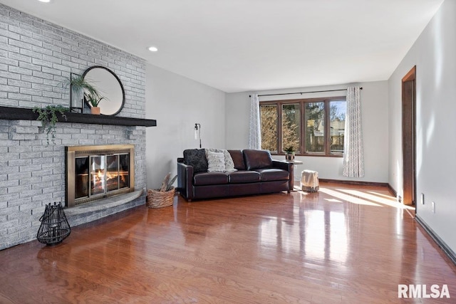 living area featuring a fireplace, baseboards, and wood finished floors