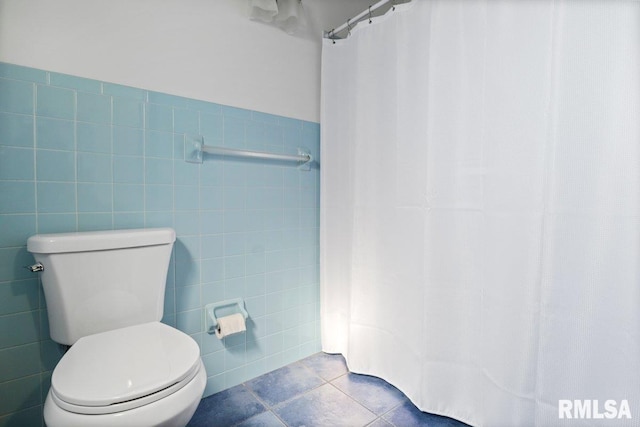 bathroom featuring a shower with shower curtain, tile walls, toilet, and tile patterned floors