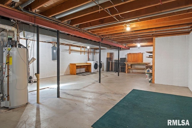 unfinished below grade area featuring gas water heater, electric panel, washer and clothes dryer, and brick wall