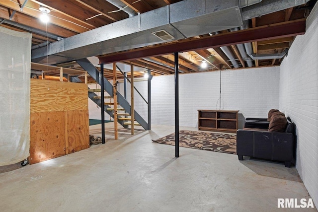 unfinished basement with stairs, brick wall, and visible vents