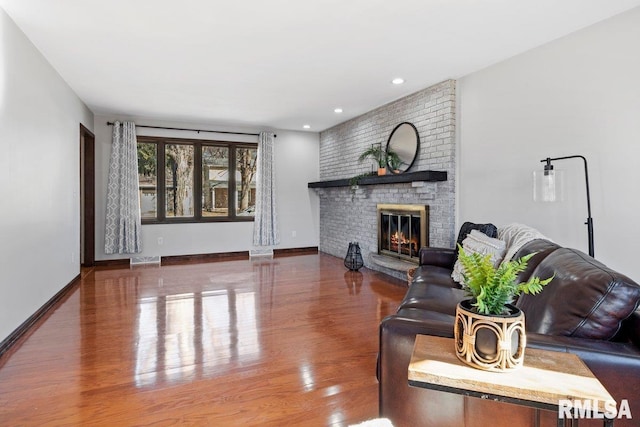 living area with recessed lighting, visible vents, a brick fireplace, wood finished floors, and baseboards