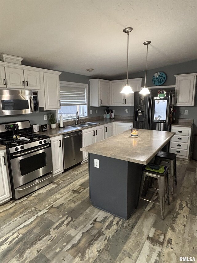 kitchen with a kitchen island, appliances with stainless steel finishes, white cabinets, and a sink