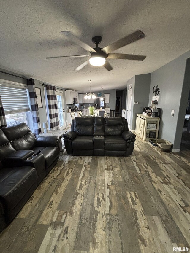 living room featuring a textured ceiling, wood finished floors, and ceiling fan with notable chandelier