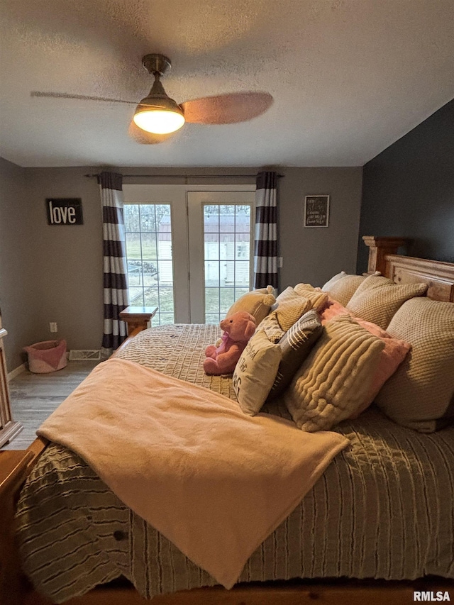 bedroom featuring ceiling fan, a textured ceiling, access to outside, and wood finished floors