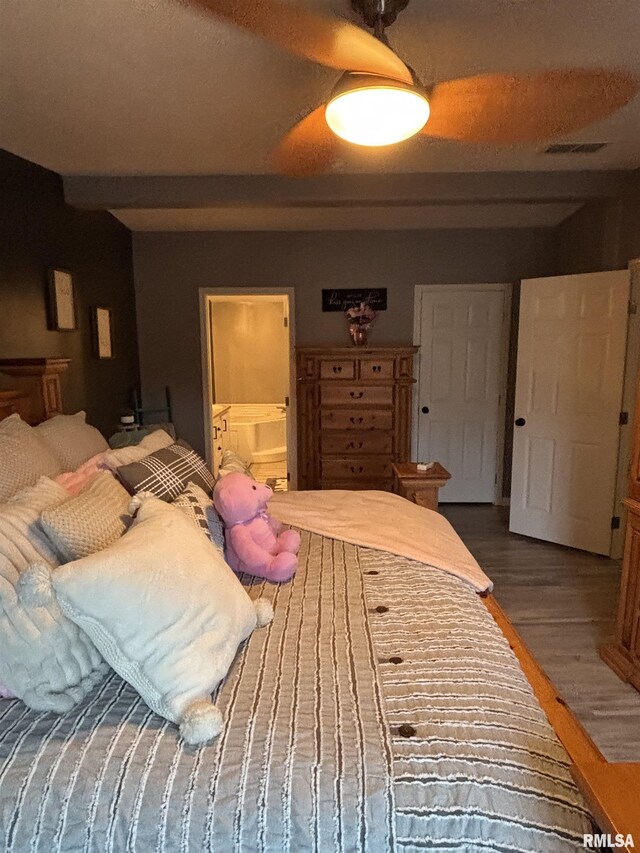 bedroom featuring ensuite bathroom, wood finished floors, and visible vents