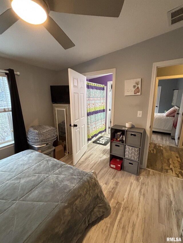 bedroom featuring ceiling fan, visible vents, vaulted ceiling, and wood finished floors