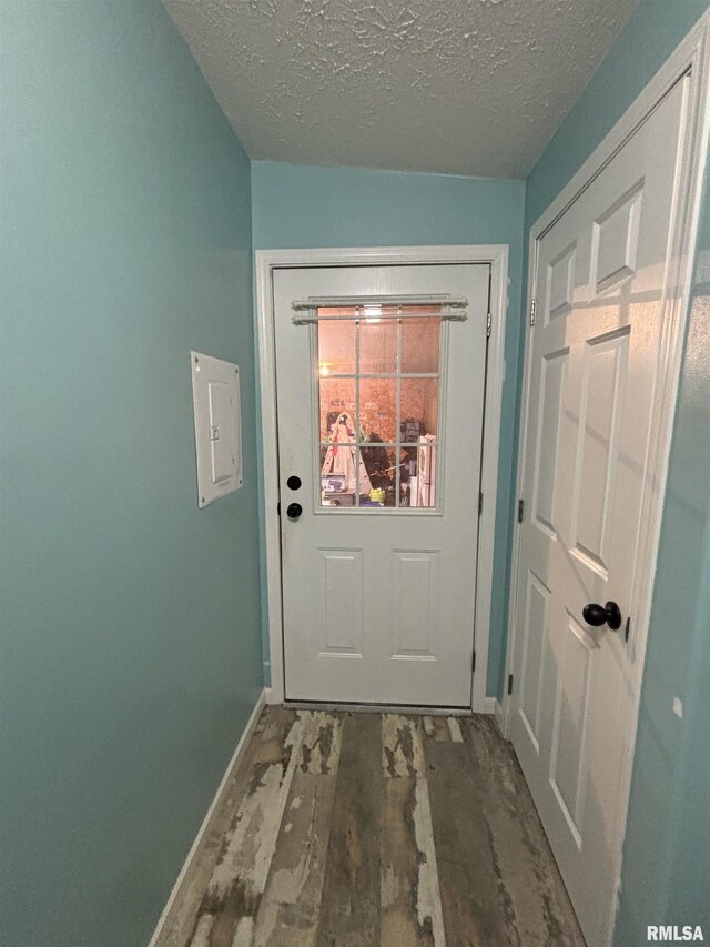 entryway with a textured ceiling, baseboards, and wood finished floors