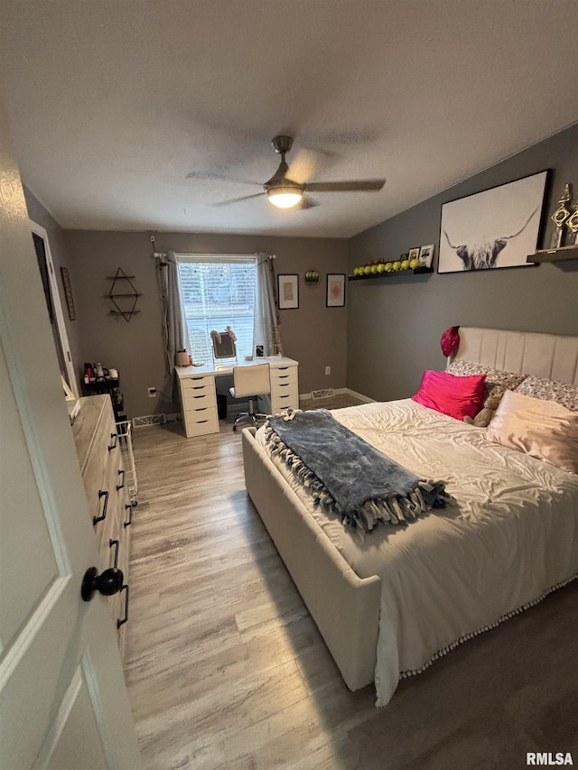 bedroom featuring baseboards, ceiling fan, a textured ceiling, and light wood finished floors