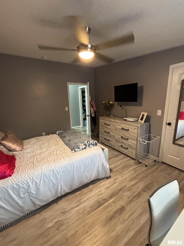 bedroom with a textured ceiling, a ceiling fan, and light wood-style floors