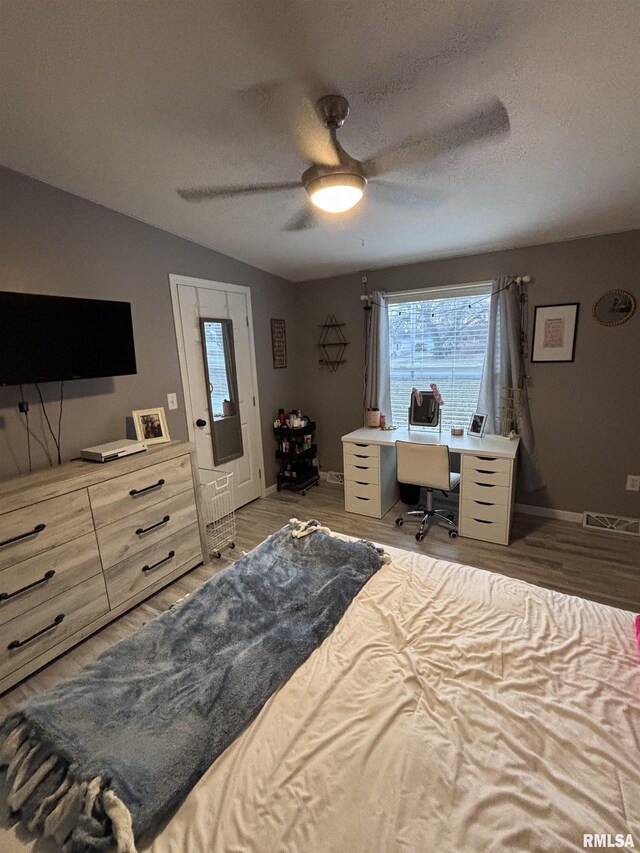 bedroom with a textured ceiling, wood finished floors, a ceiling fan, and lofted ceiling